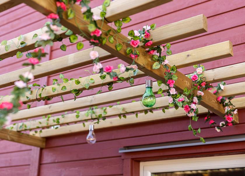 blommor och lampor hänger i träbalkar på uteplats