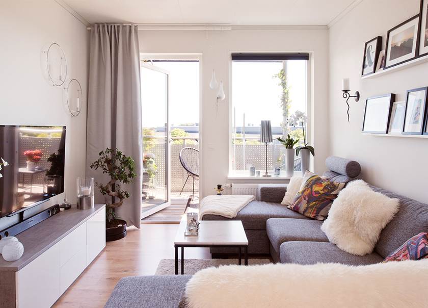 Vardagsrum med plats för soffa, soffbord och tv i BoKlok lägenhet med öppen dörr ut till balkongen hemma hos Malmborg Vardagsrum med plats för soffa, soffbord och tv i BoKlok lägenhet med öppen dörr ut till balkongen hemma hos Malmborg