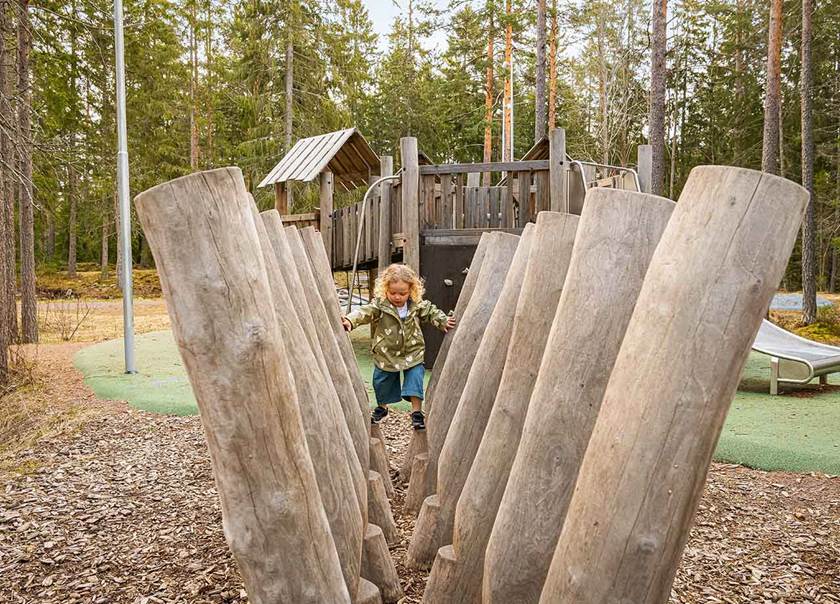 Flicka leker på lekplats och klättrar på stockar.n.