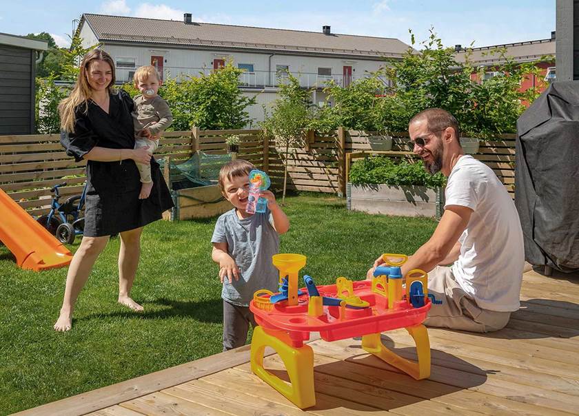 Familj två vuxna två barn leker med sopbubblor på altan till BoKlok radhus i Tungelsta.