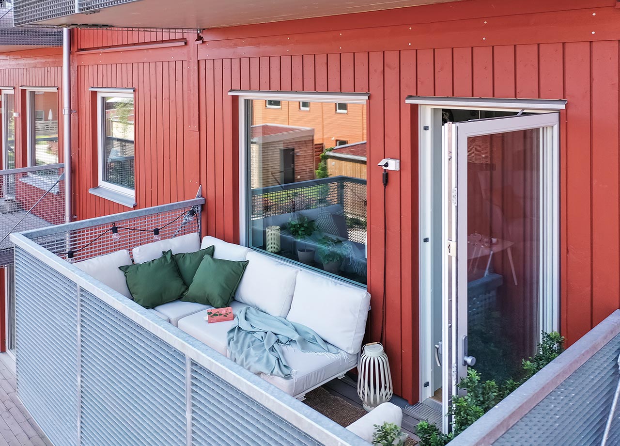 Foto av balkong till BoKlok lägenhetshus med röd träfasad.