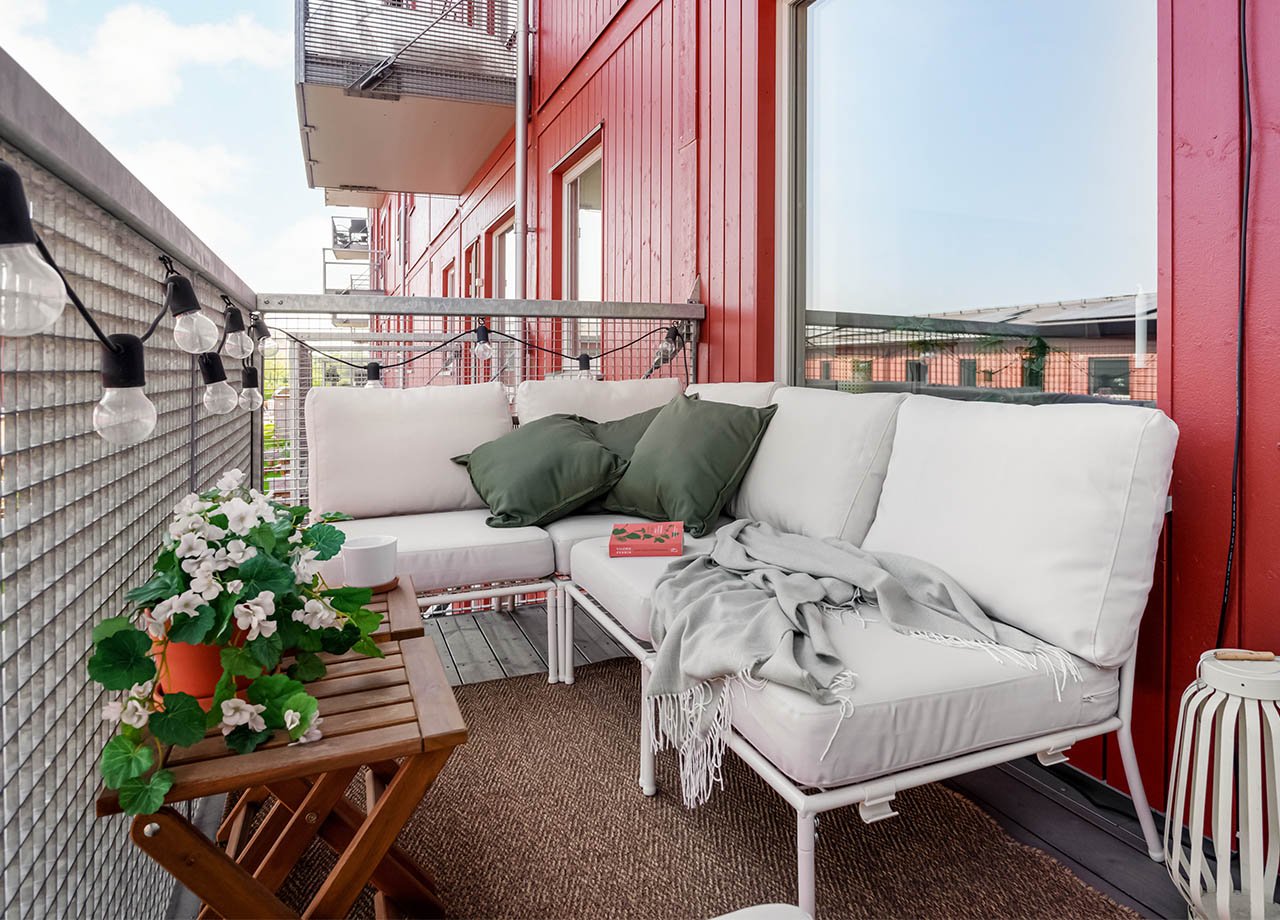 Foto av balkong till en BoKlok lägenhet med röd träfasad. 