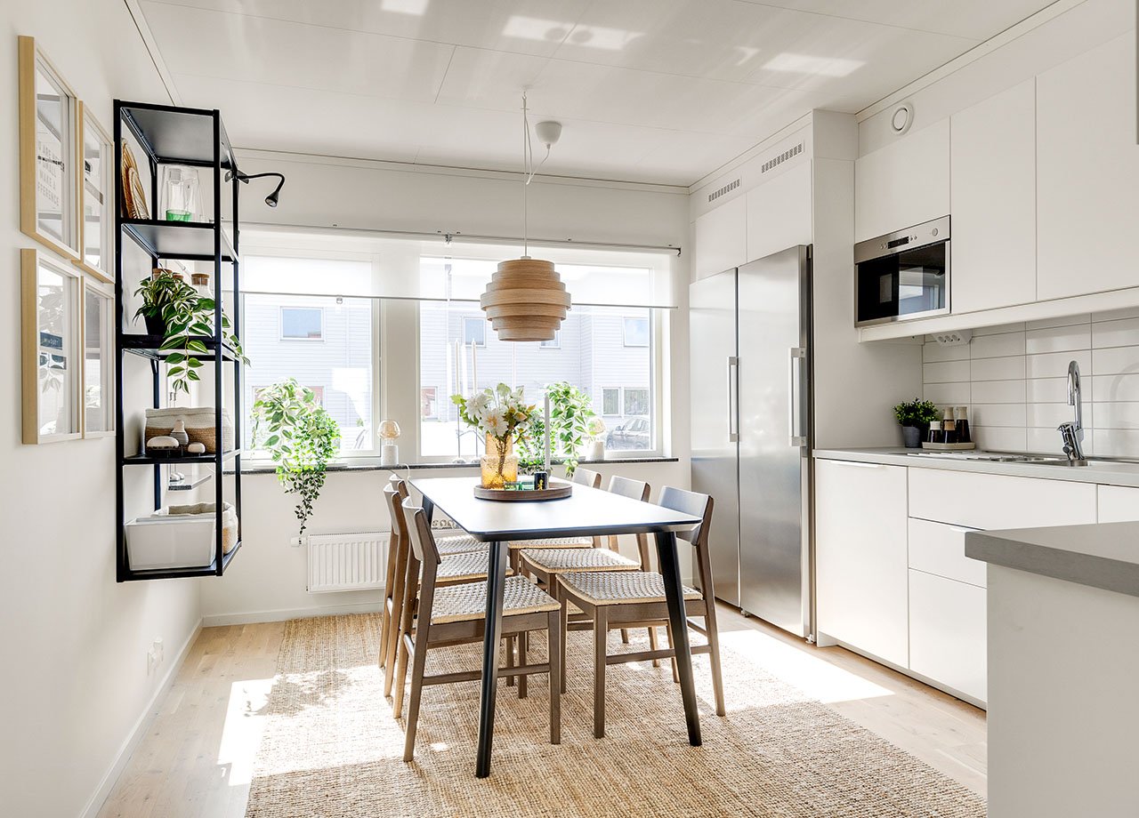 Kök med vita köksluckor och rostfria vitvaror och matbord med 4 stolar i BoKlok radhus 117 kvm